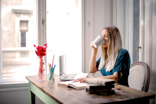 Womatn Sitting on Chair While Drinking on White Ceramic Mug