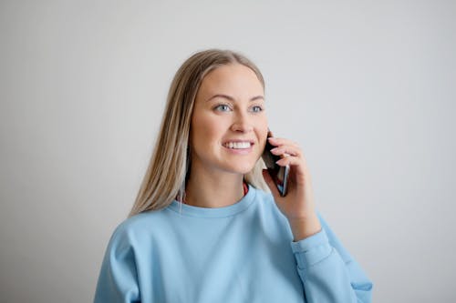 무료 그녀의 전화를 들고 파란색 크루 넥 긴 소매 셔츠에 여자 스톡 사진