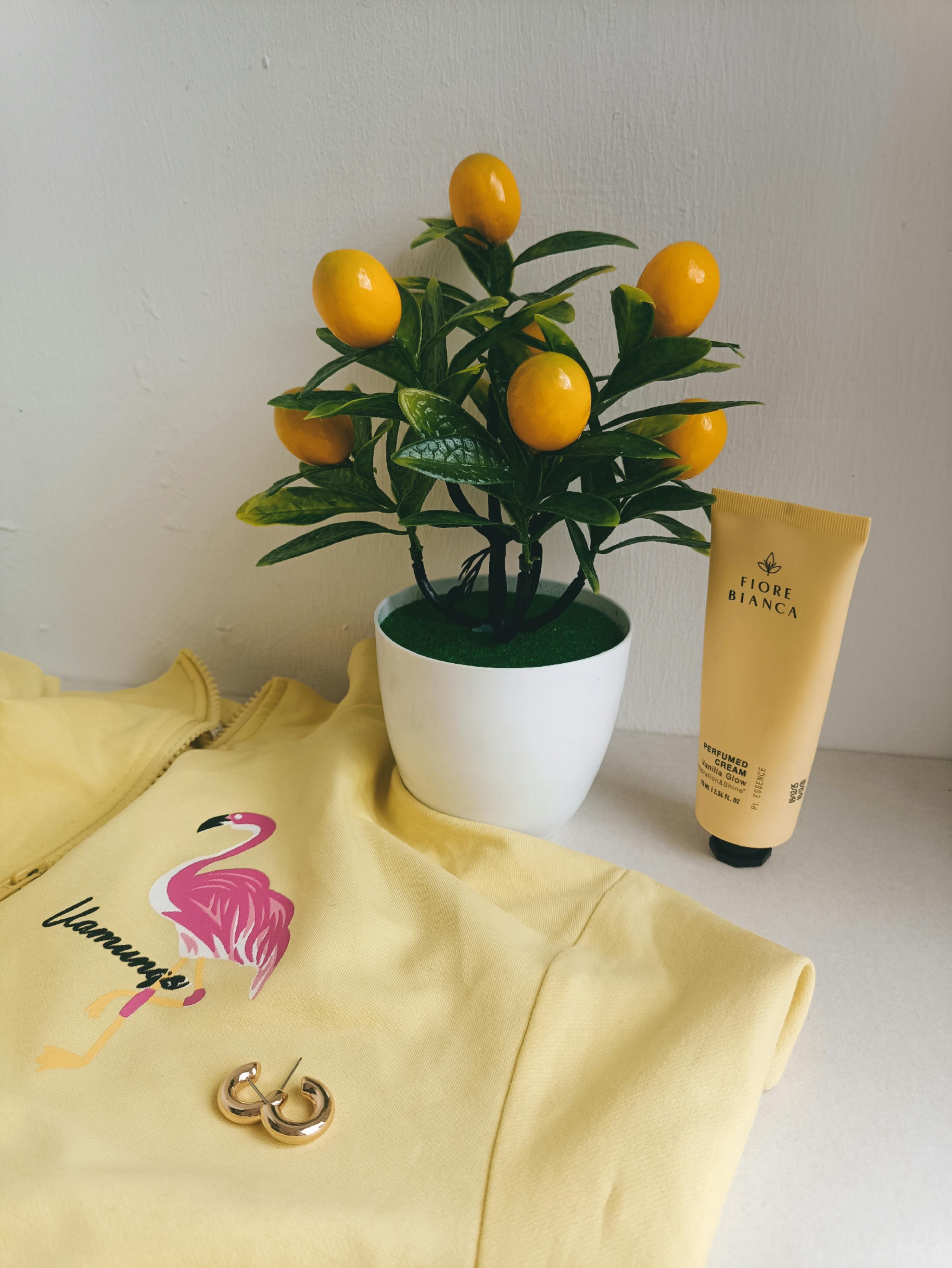 Vibrant yellow outfit paired with citrus plant and skincare for a fresh look.