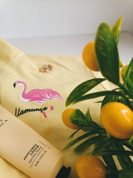 Vibrant summer flat lay featuring a yellow flamingo shirt, lemon plant, and skincare tube.