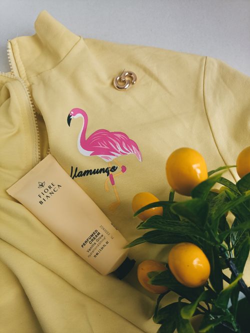 Free A cozy yellow jacket with a flamingo print, skincare cream, and kumquat branch for a vibrant lifestyle vibe. Stock Photo