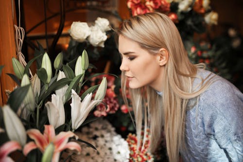 花の香りをしながら灰色のセーターを着ている女性