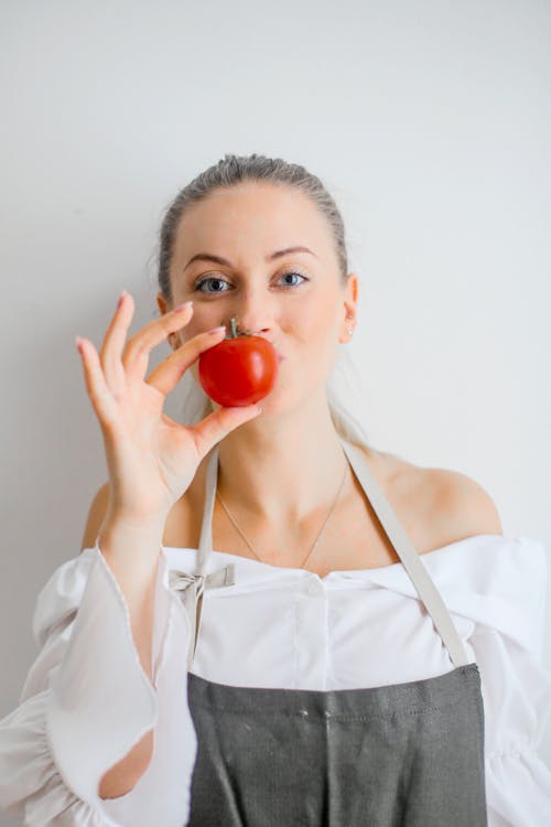 Woman in White Spaghetti Strap Top Holding a Tomato