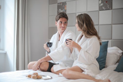 Free Woman in White Robe Sitting Beside Man on Bed Stock Photo