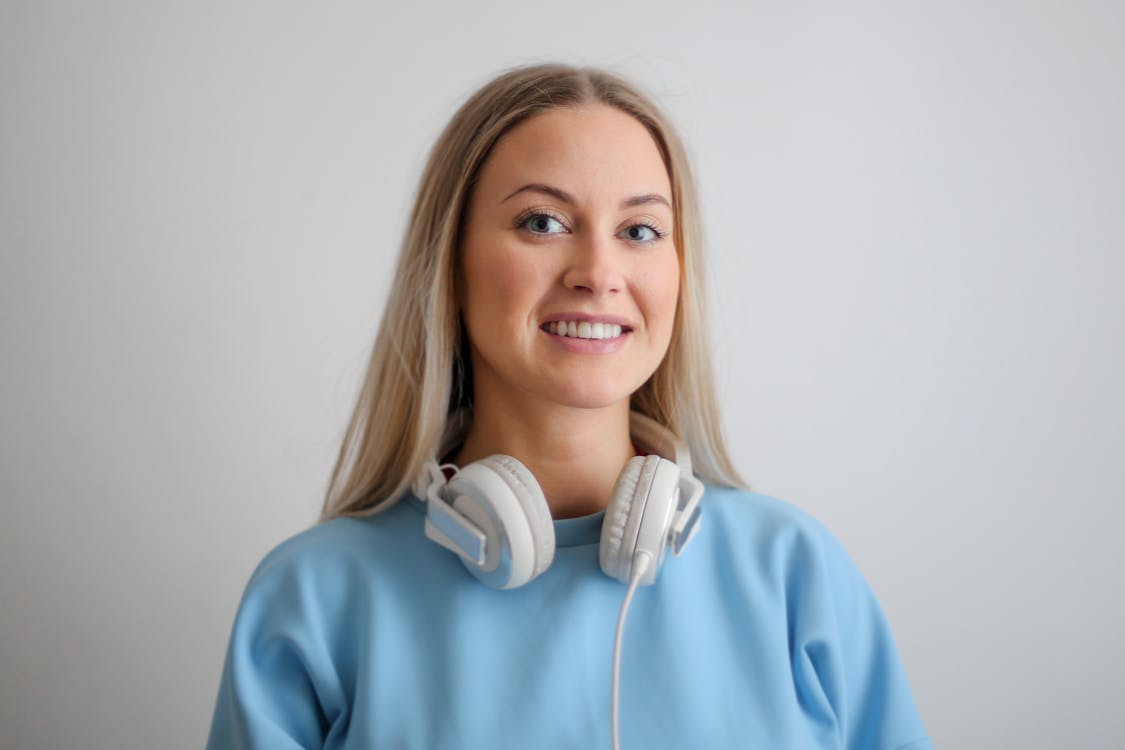 Free Woman in Blue Long Sleeve Shirt Wearing White Headphones Stock Photo