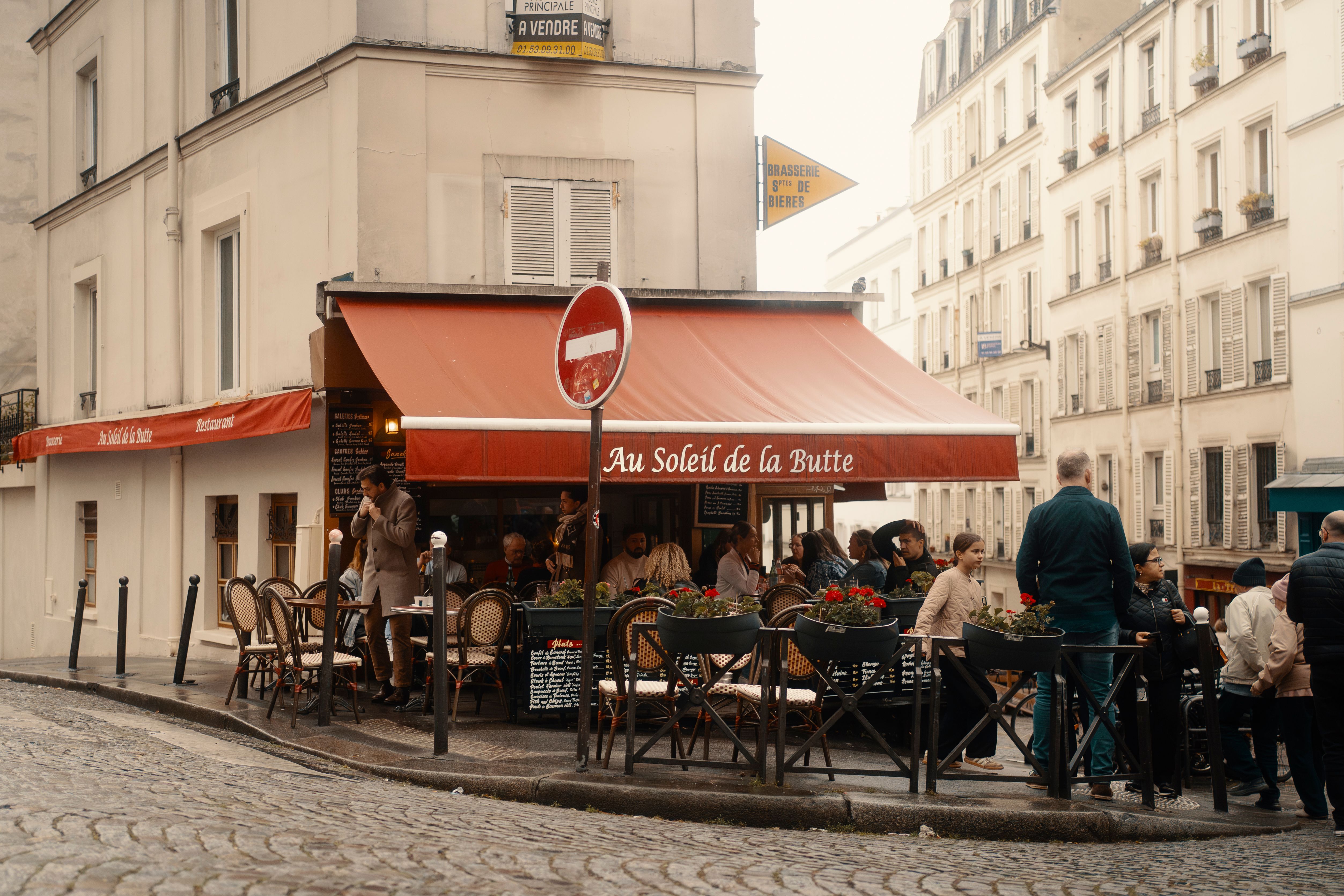 Charming scene of people enjoying a cafe in Montmartre, Paris. Cozy, bustling atmosphere.