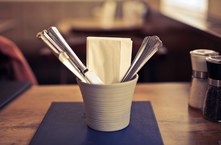 Close-up of elegant table with silverware and napkin in focus. Ideal for dining themes.