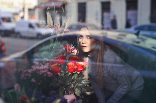 Woman in Gray Long Sleeve Shirt Holding Red Roses