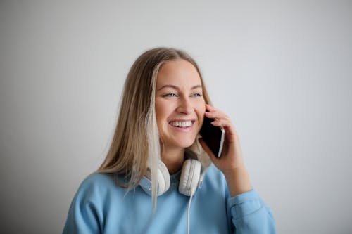 Woman in Blue Long Sleeve Shirt Holding Black Smartphone