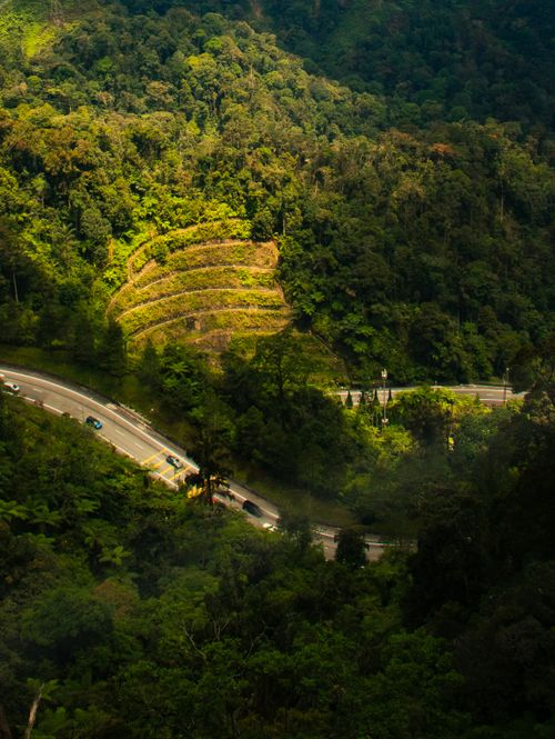 Free Aerial view of a scenic highway winding through lush forests in Kuala Lumpur, Malaysia. Stock Photo