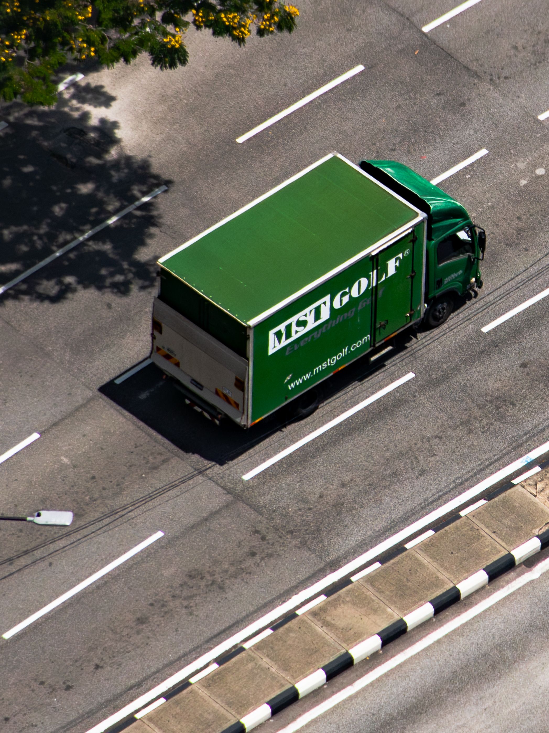 Aerial shot of a green delivery truck on a city road in Kuala Lumpur.