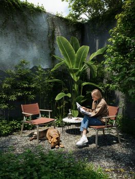A person reads peacefully in a leafy garden, enjoying nature on a sunny day.