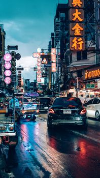 Bustling street scene in Bangkok, Thailand showcasing neon lights and busy traffic at night.
