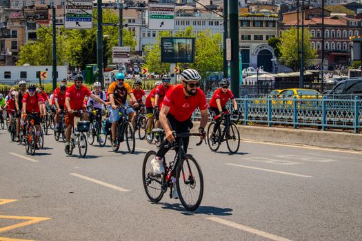 Group of cyclists wearing red jerseys riding through Istanbul, capturing urban buzz.