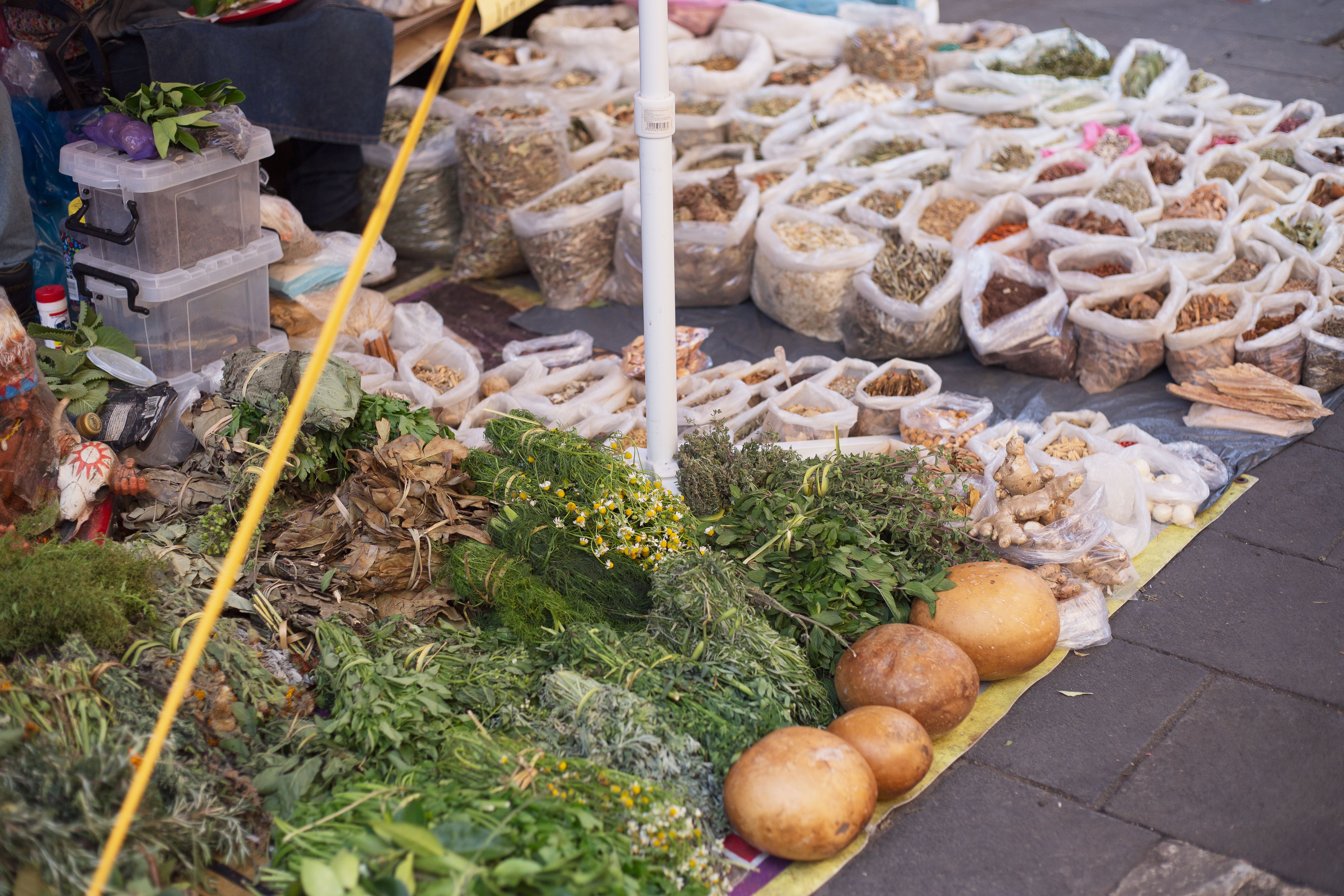 Diversas hierbas y especias expuestas en un puesto de un mercado mexicano al aire libre.