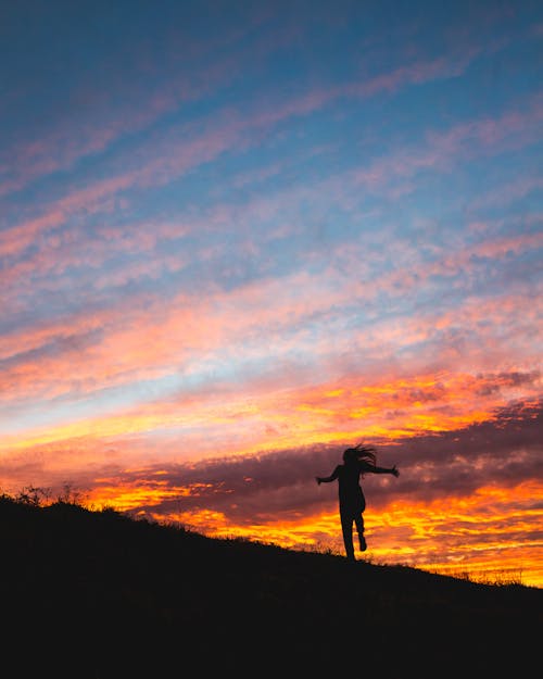 Silhouetfoto Van Persoon Die Tijdens Zonsondergang Op Heuvel Staat