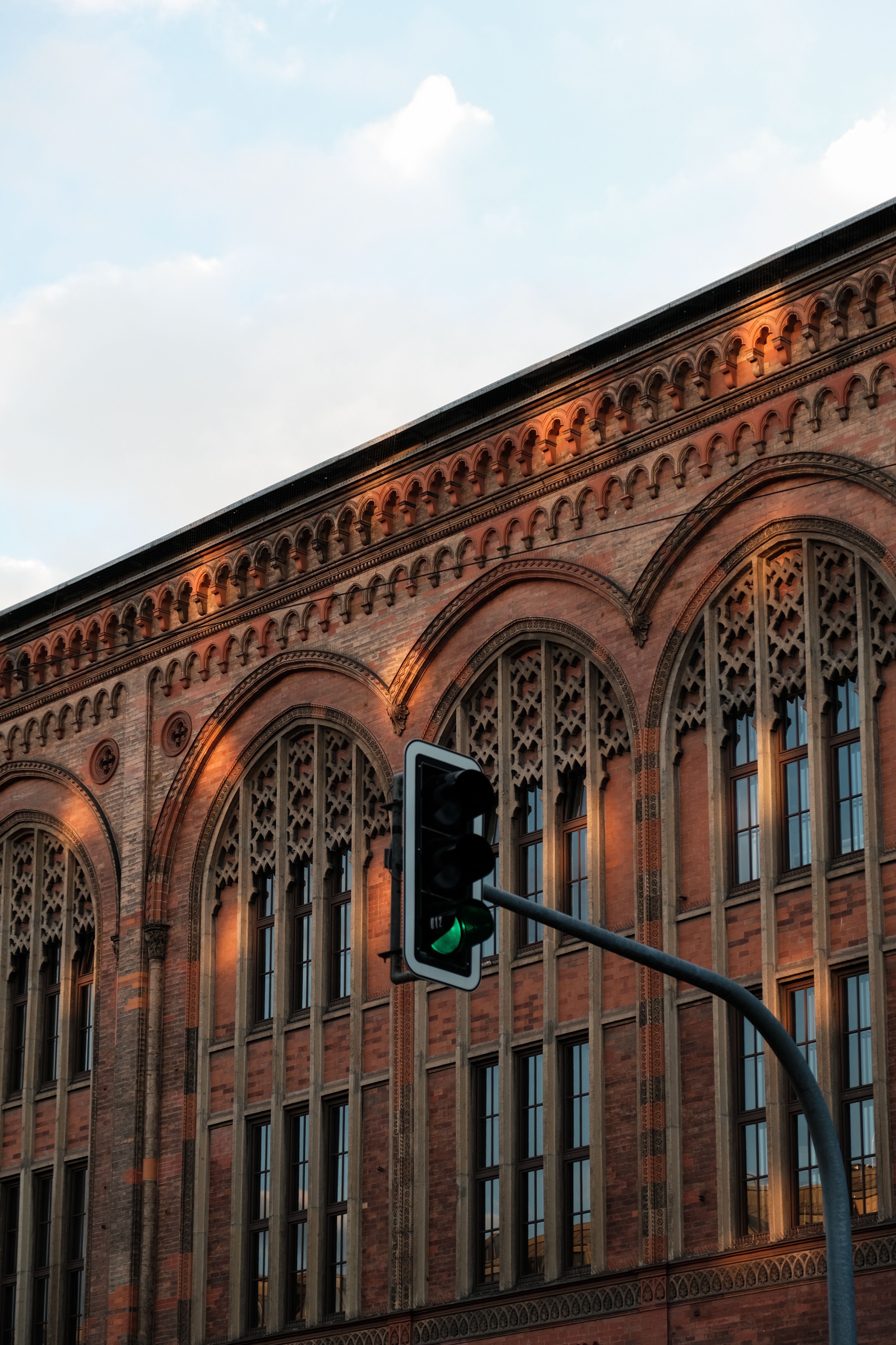 Elegant Gothic revival architecture illuminated by sunset with a traffic light in view.
