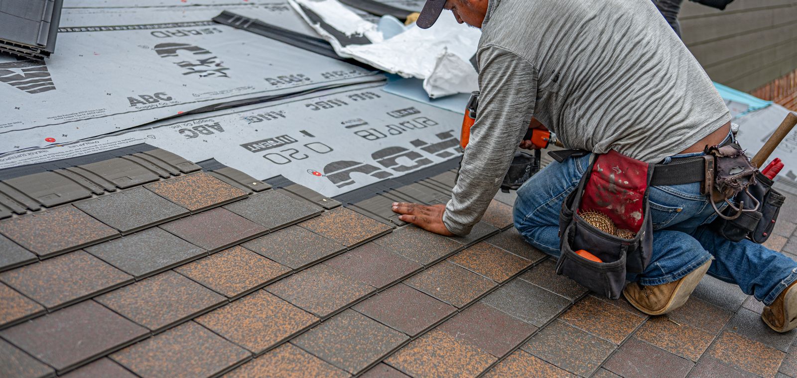 Roofer installing asphalt shingles on a house