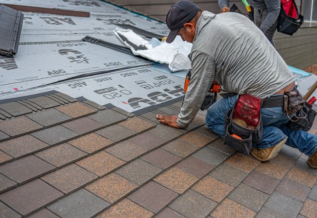 Roofer installing asphalt shingles on a house