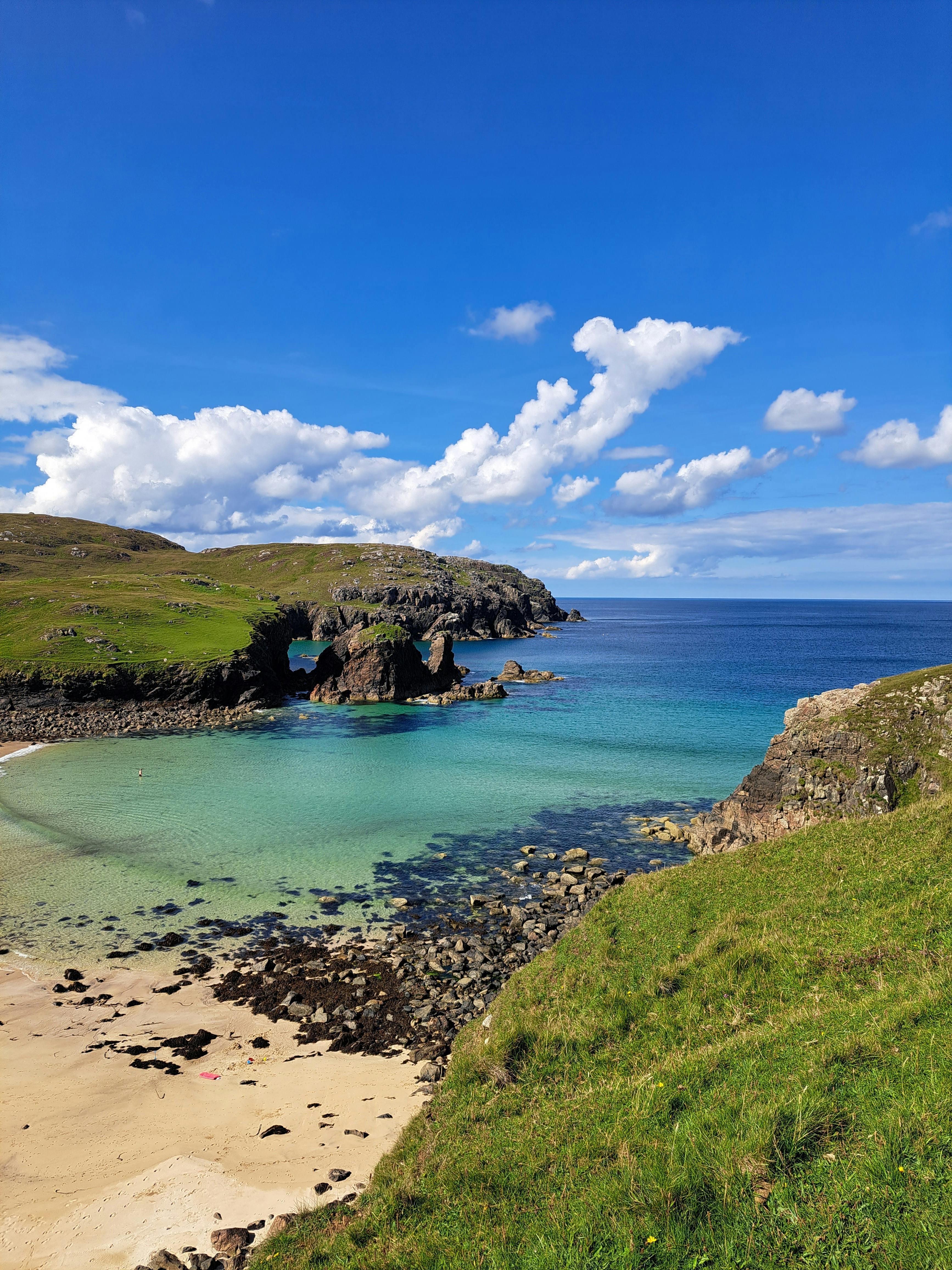 Breathtaking coastal landscape with clear blue sea and grassy cliff under a vibrant sky.
