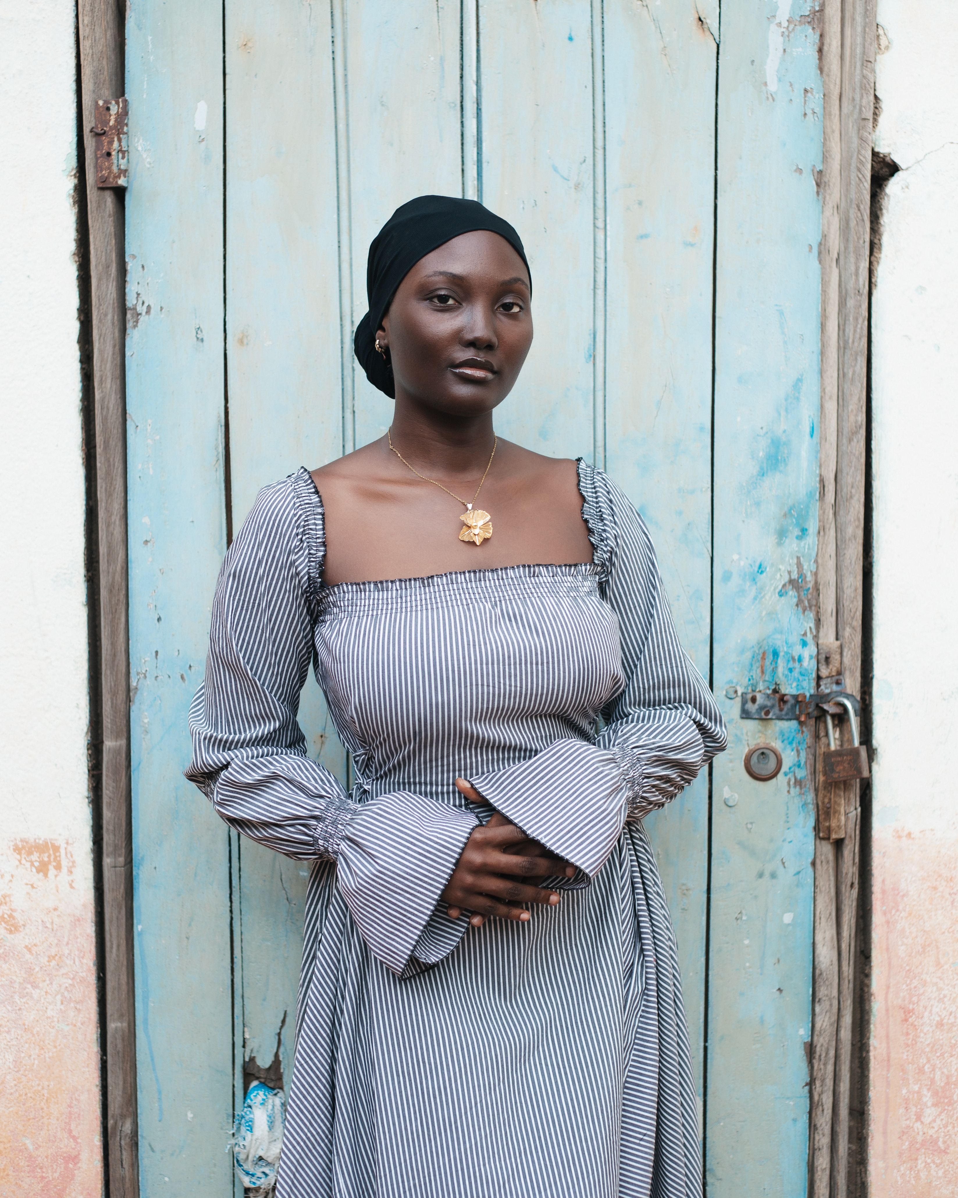 Portrait of a stylish African woman standing against a rustic door.