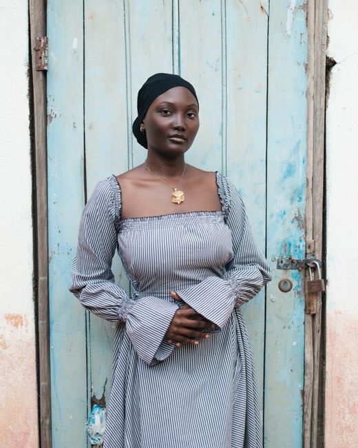 Portrait of a stylish African woman standing against a rustic door.
