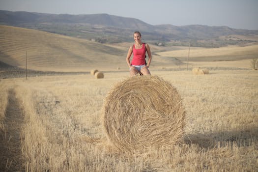 Female traveler relaxing on a hay bale in a rural summer landscape.