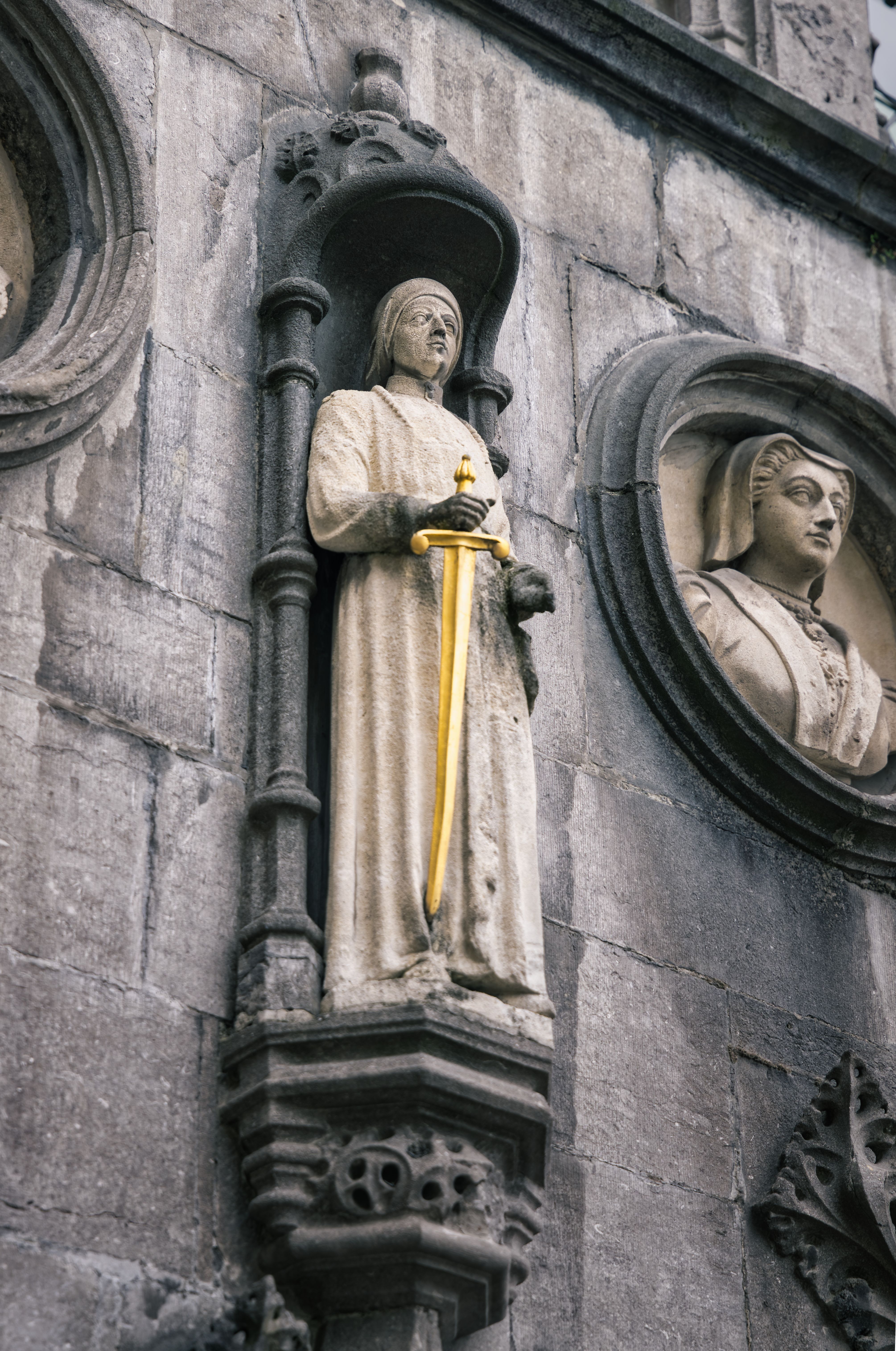 Intricate stone statues adorn the Bruges cathedral facade, showcasing medieval craftsmanship.