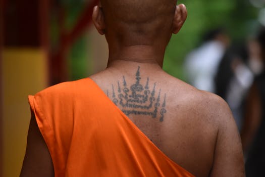 Thoughtful moment of a tattooed monk amidst spirituality in Bangkok temple.