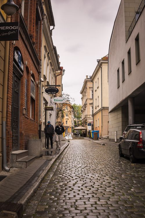 Free View of a picturesque cobblestone street in a European city with historic architecture. Stock Photo
