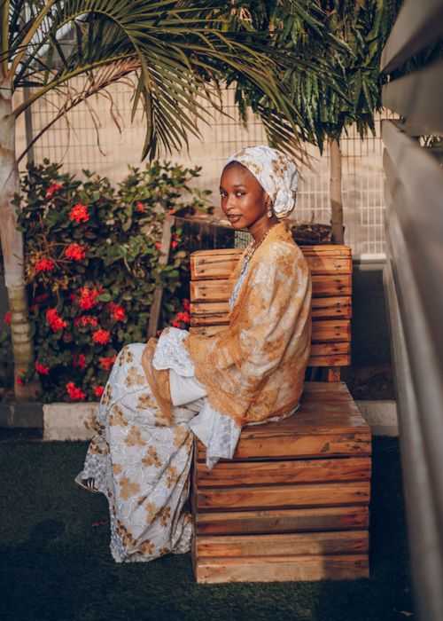 Free A Nigerian woman in traditional attire sits outdoors, exuding elegance and cultural beauty. Stock Photo