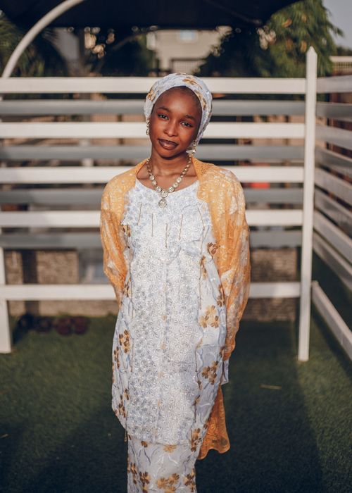 Free Portrait of a young Nigerian woman dressed in colorful traditional attire, standing outdoors. Stock Photo