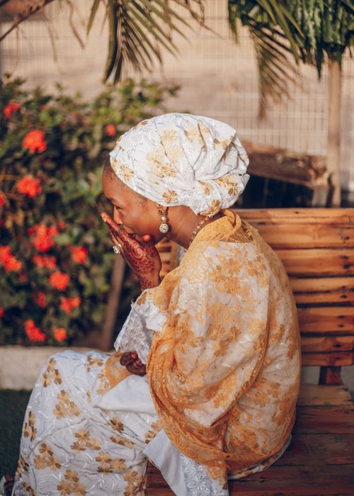Free Woman in colorful Nigerian attire sitting outdoors in sunlight, embodying cultural elegance. Stock Photo