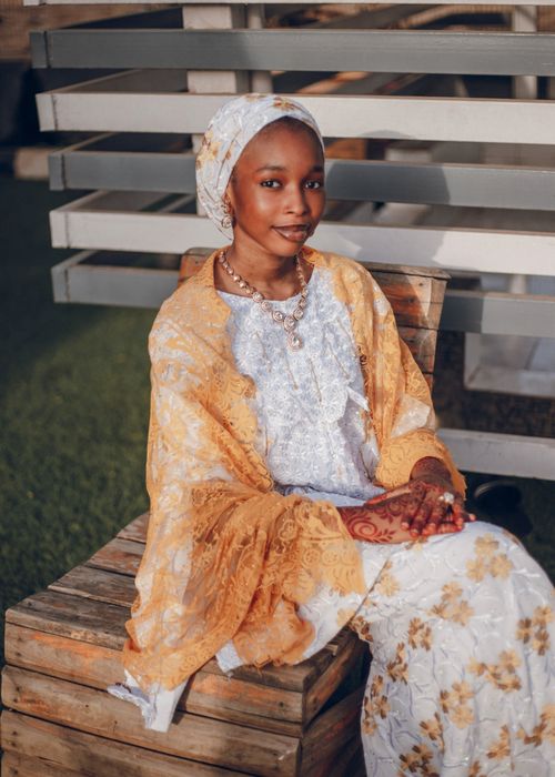 Free A young woman in colorful traditional Nigerian attire sits outdoors, capturing cultural beauty. Stock Photo