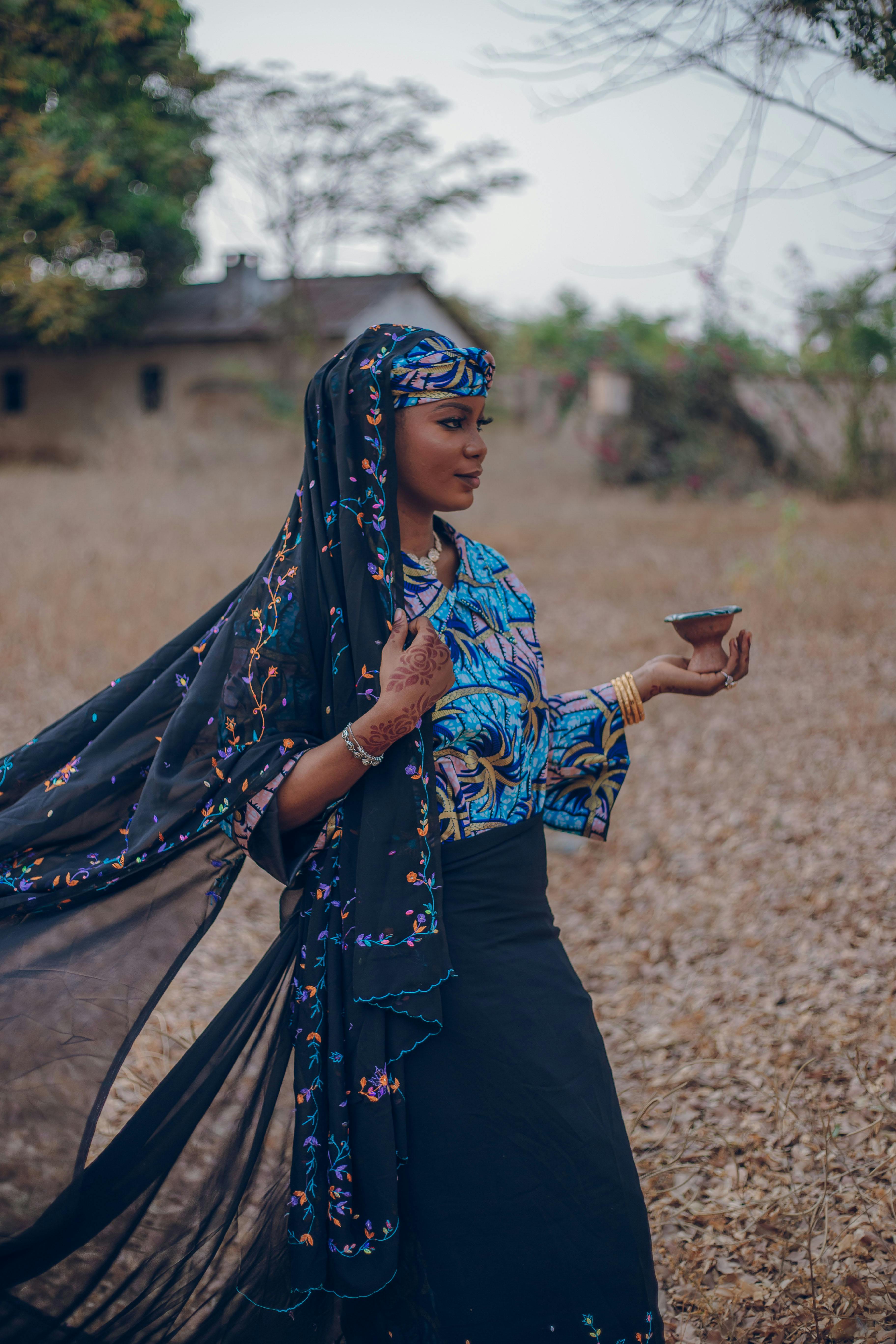 A young woman in vibrant Nigerian attire gracefully poses outdoors, capturing cultural beauty.