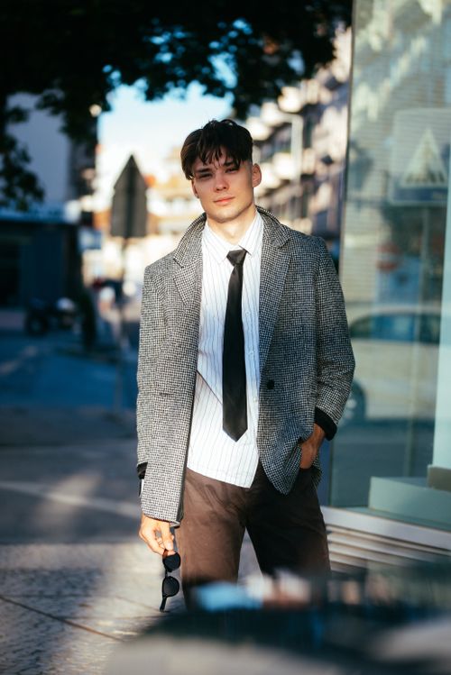 Free A young man in smart casual attire poses confidently on a city street. Stock Photo