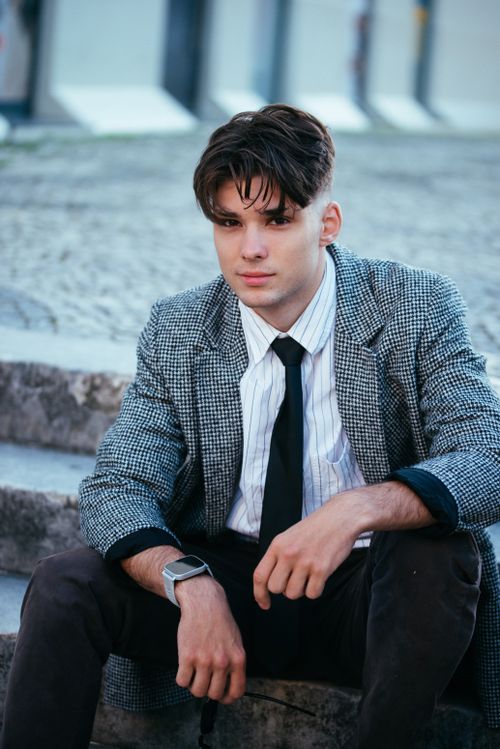 Free Confident young man in smart casual attire sitting on urban steps outdoors. Stock Photo