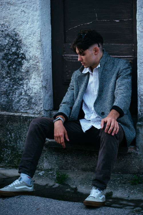 Free Stylish young man in a blazer sitting outdoors, exuding cool urban fashion. Stock Photo