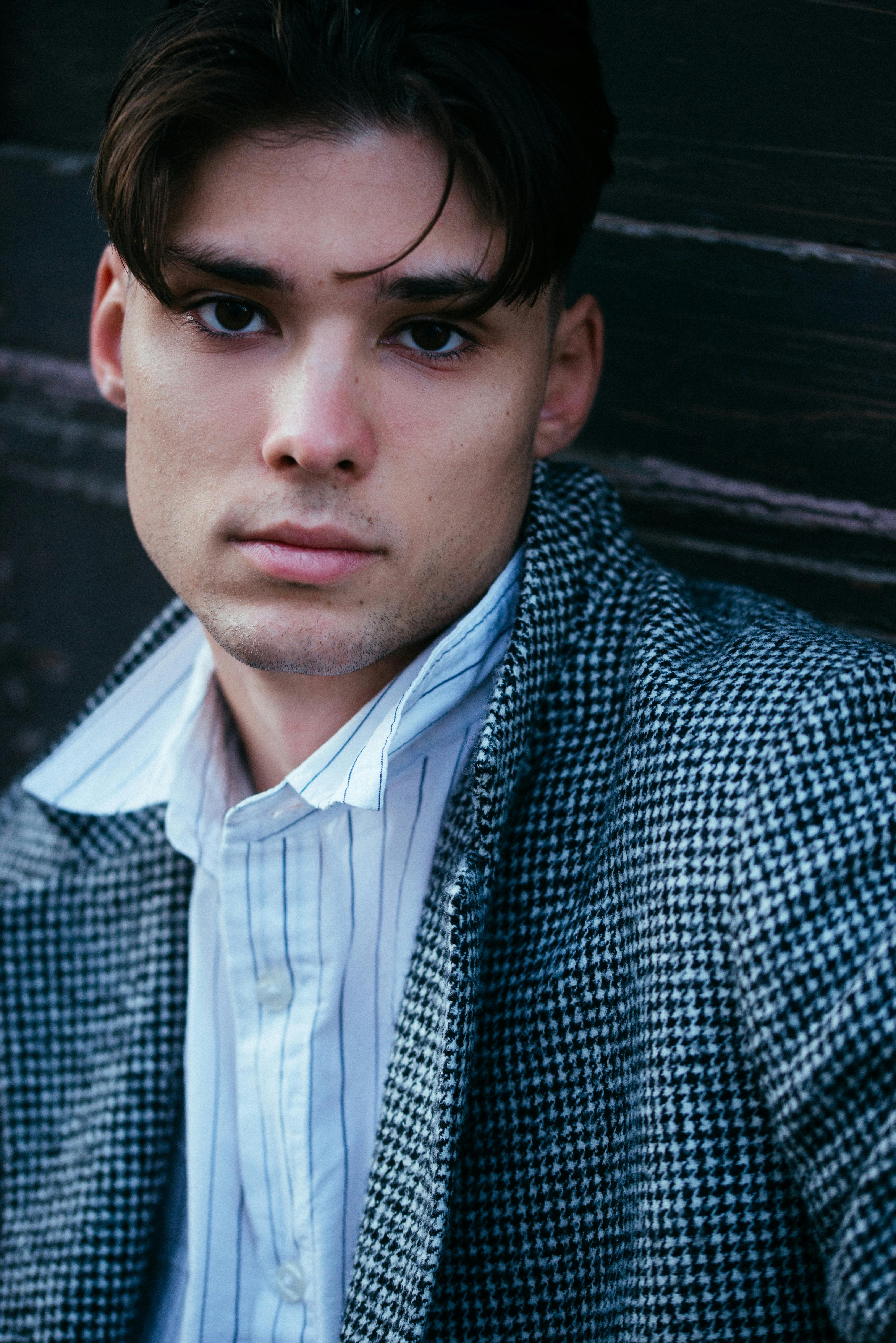 Close-up portrait of a young man in stylish urban fashion with a contemplative expression.