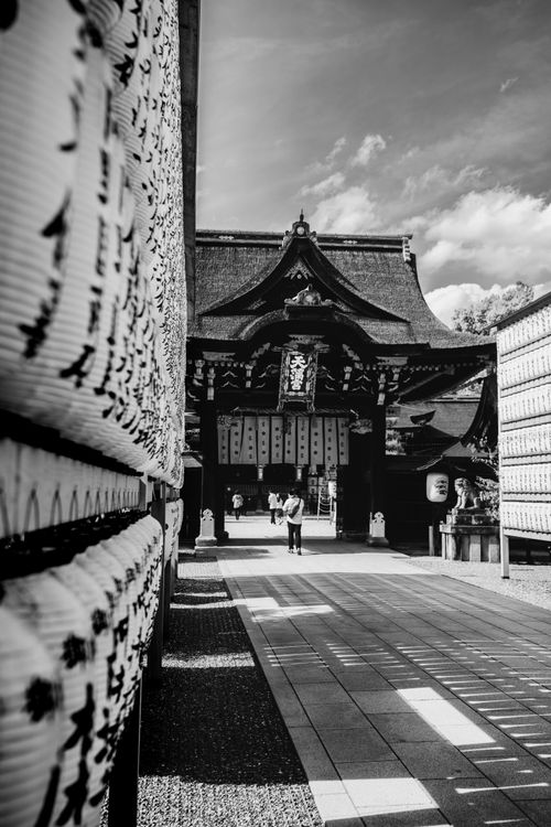 Free Black and white photo of a historic Japanese temple entrance with people walking on a sunny day. Stock Photo