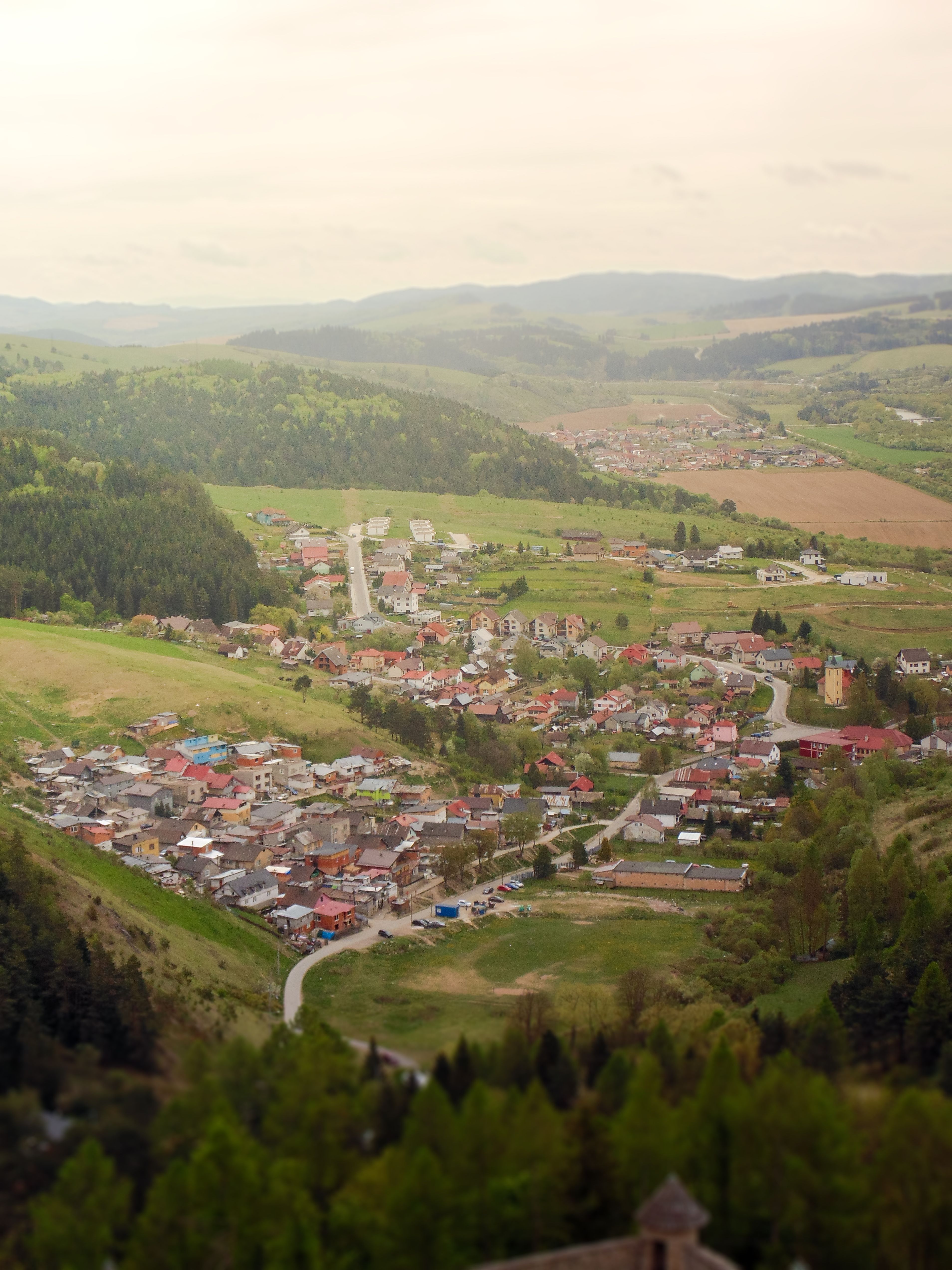 Aerial shot of a scenic countryside village surrounded by lush hills and greenery.