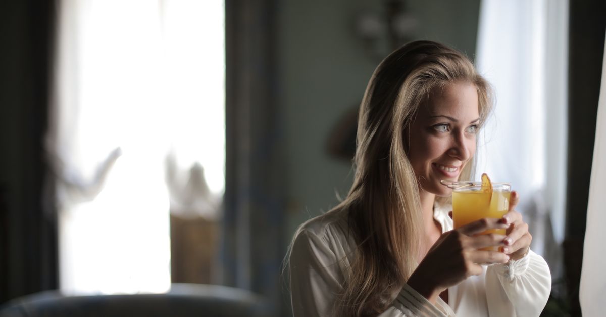 woman drinking water by window in morning light