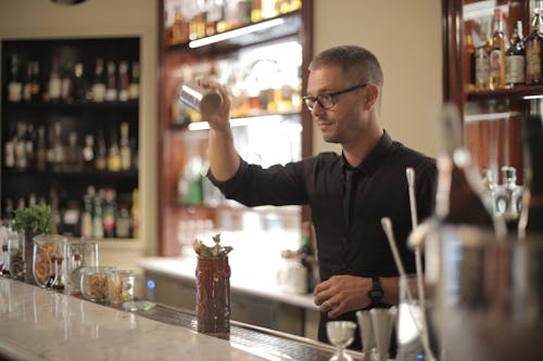 Man in Black Long Sleeve Shirt Mixing Drink