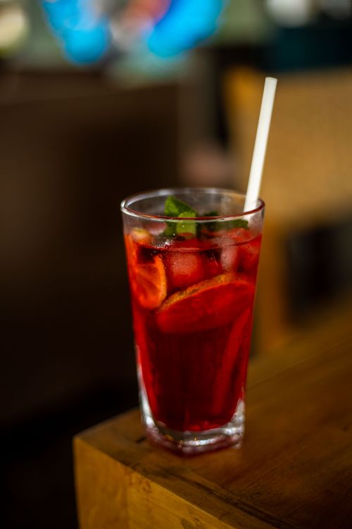 Free Chilled red berry beverage with ice and mint in a glass on a wooden table. Stock Photo