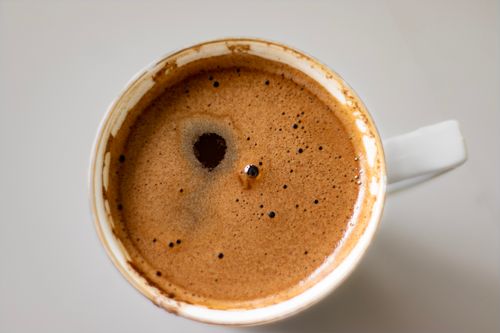 Free A detailed close-up of a coffee cup with frothy surface, captured from above. Stock Photo