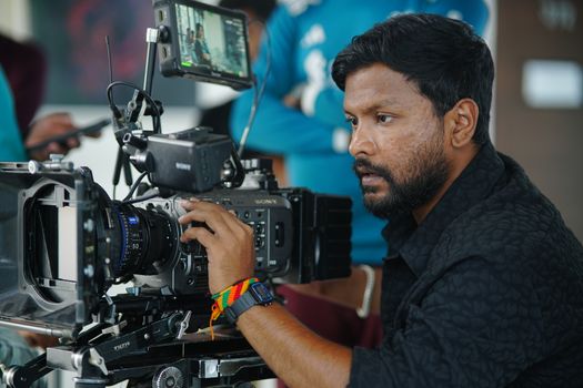 Focused cameraman operating professional video equipment indoors in Dhaka.