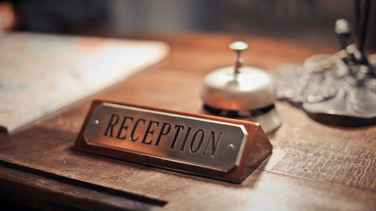Close-up of a hotel reception desk where a guest reviews an itemized folio at checkout