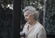 一位白发、佩戴珍珠的资深女性在室内享受着安静的时刻