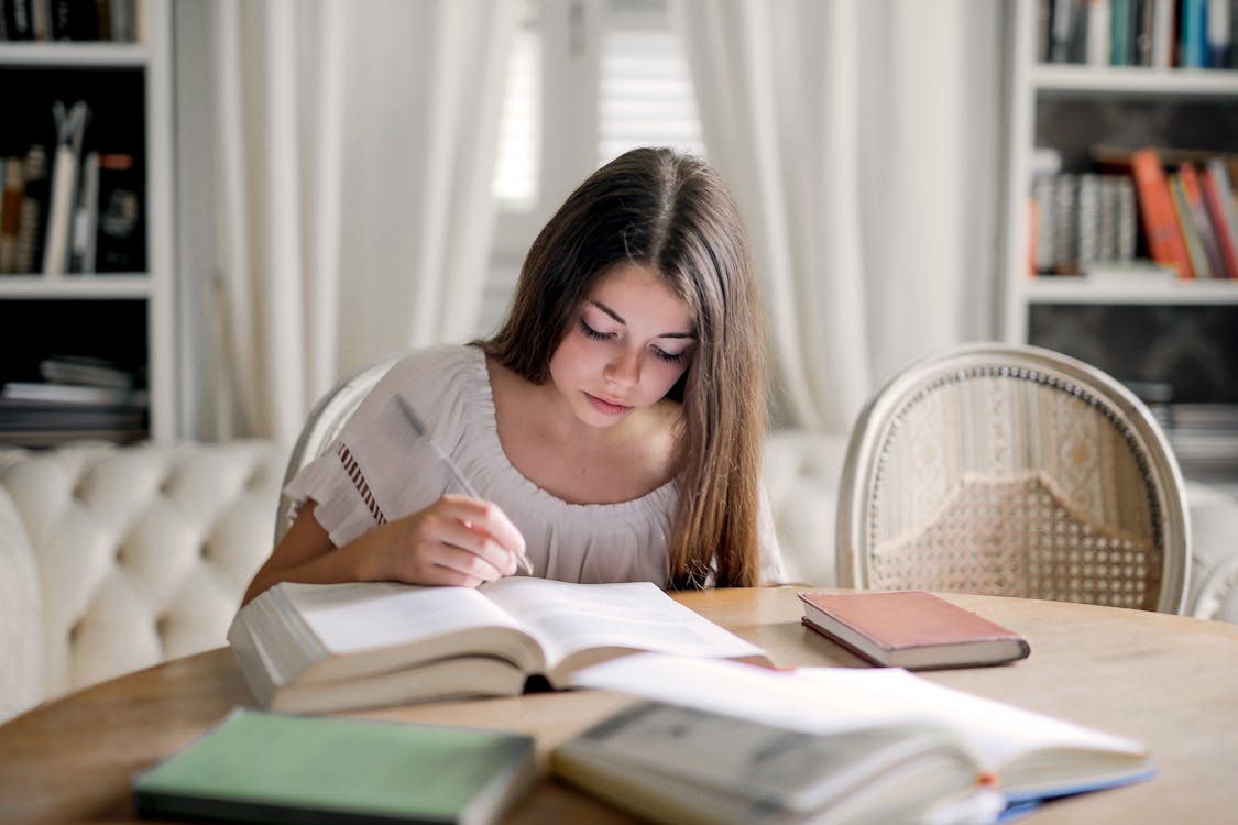 Woman in White Long Sleeve Shirt While Reading Book