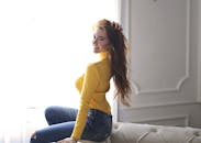 一位穿着黄色毛衣的快乐女人坐在室内微笑的肖像